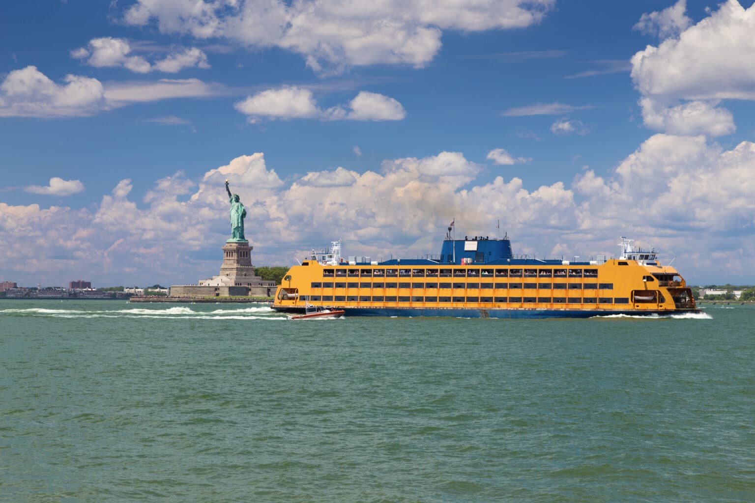 Statue of Liberty, Staten Island Ferry, Water of New York Harbor, Coast Guard Boat and Blue Sky with Clouds, New York City.