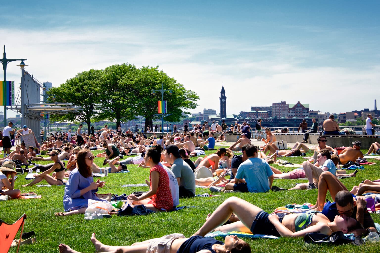 Large group of people in Hudson River Park, Manhattan with Hoboken, NJ in the background, New York City, USA
