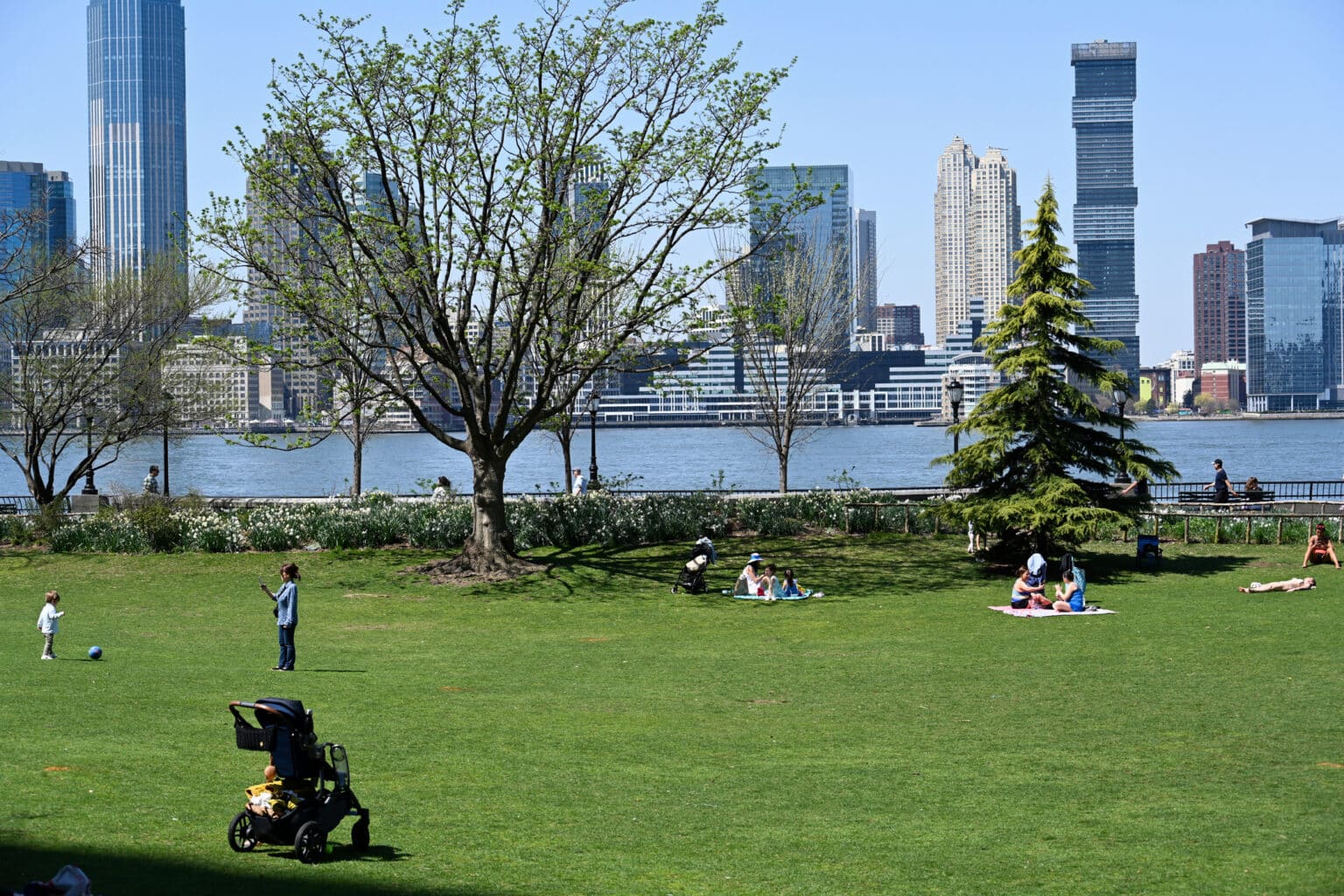Tourists and locals relax in Hudson River Park in Lower Manhattan on a warm spring day.