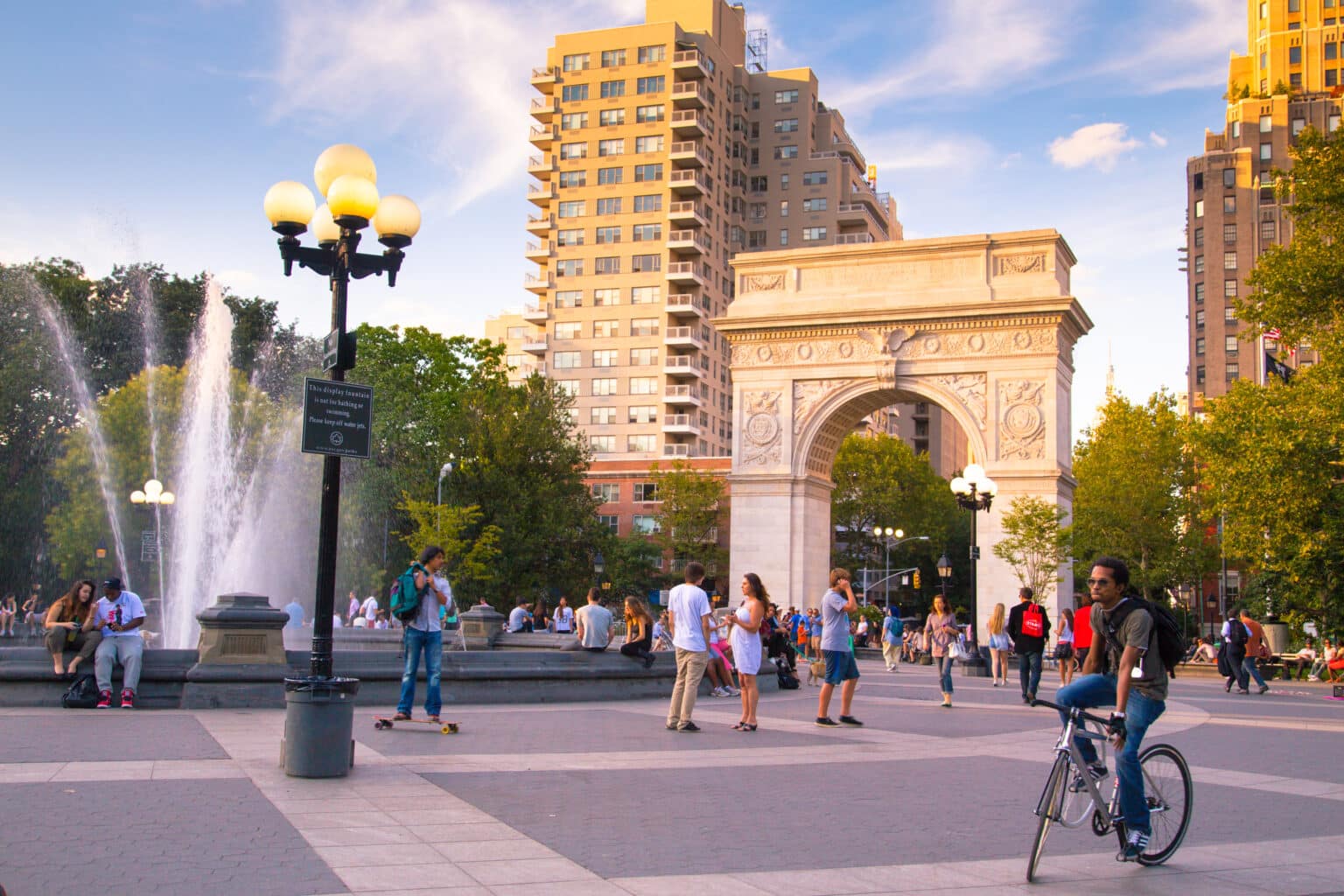 New York City, NY, USA - August 15, 2013: View of Washington Square Park in Manhattan with landmark arch and visitors present on a summer evening. Washington Square Park is a 9.75 acre park located in Greenwich Village and is a popular meeting spot.
